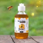 Envase de 330g de Miel natural Apícola Biomiel con dosificador en primer plano, destacando su color ámbar y textura.