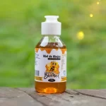 Envase de 180g de Miel natural Apícola Biomiel con dosificador en primer plano, destacando su color ámbar y textura.